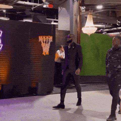 a man in a suit is walking in a room with a green screen behind him .