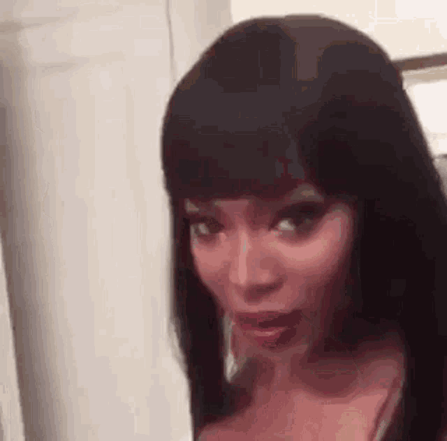 a close up of a woman with long black hair and bangs making a funny face .