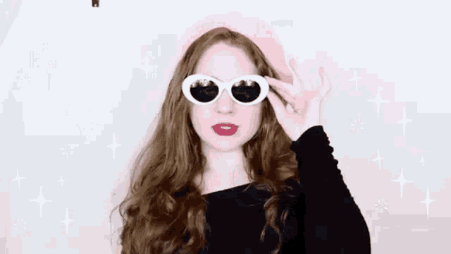 a woman wearing sunglasses and a pink beret is making a peace sign .