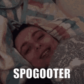 a woman is laying in bed under a blanket with the words spogooter written on the bottom of her face .