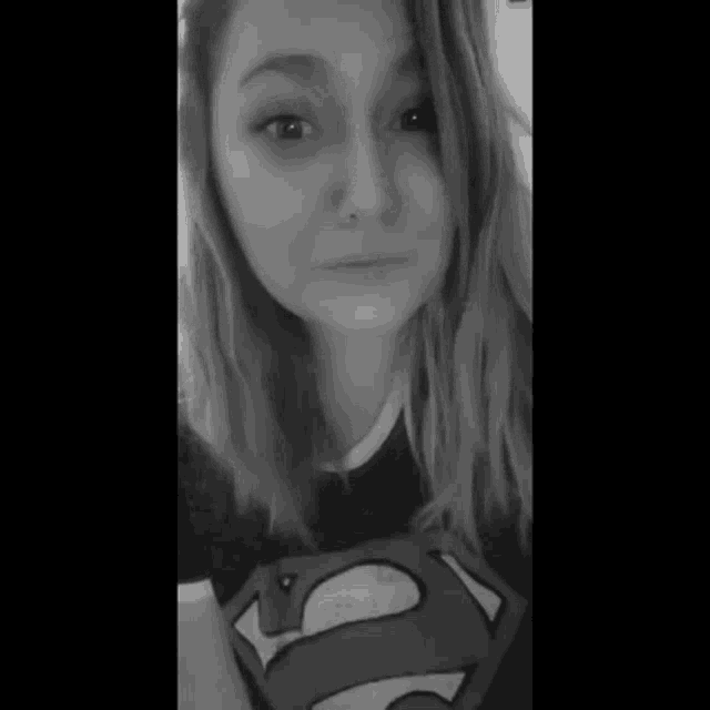 a woman is wearing a superman shirt and looking up at the camera .