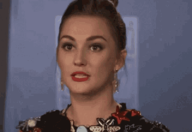 a woman with a surprised look on her face is wearing a dress and earrings .