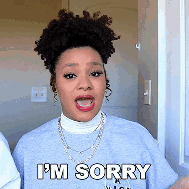 a woman wearing a grey shirt that says i 'm sorry on it