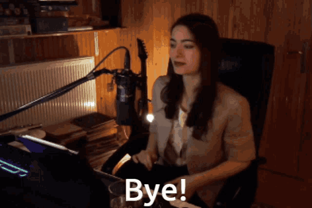a woman sitting in front of a microphone with the words bye written on the screen
