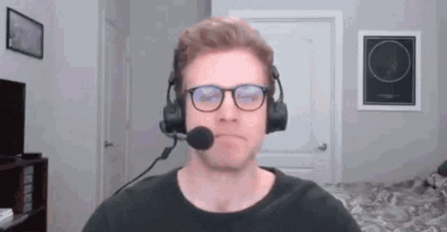 a man wearing glasses and a headset with a microphone is sitting in a living room .