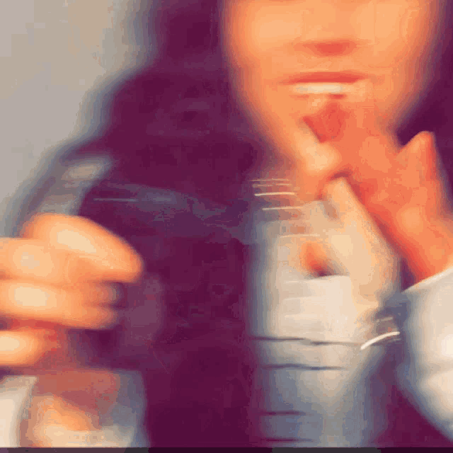 a blurry photo of a person 's face with their fingers on their mouth