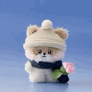 a stuffed animal is wearing a hat and scarf and holding a flower .