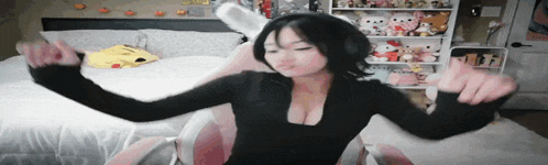 a woman is sitting in a chair with her arms outstretched in front of a bed .