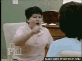 a woman in a pink shirt is talking to another woman in a chair .