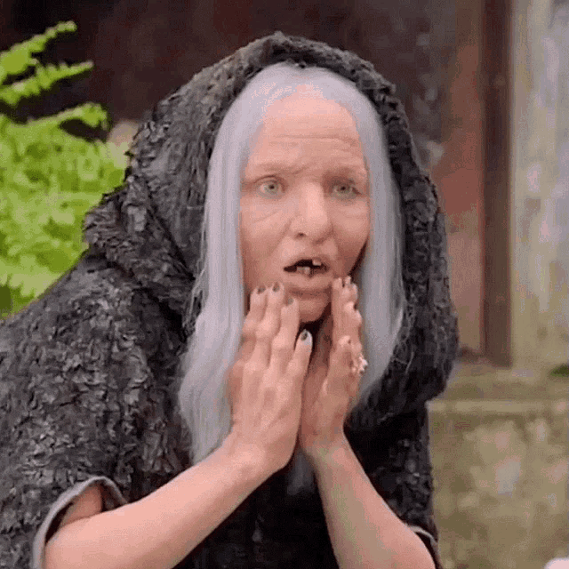 an older woman with white hair and a black cape is making a funny face .