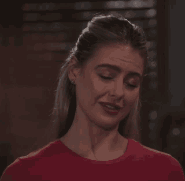 a woman wearing a red shirt is making a funny face