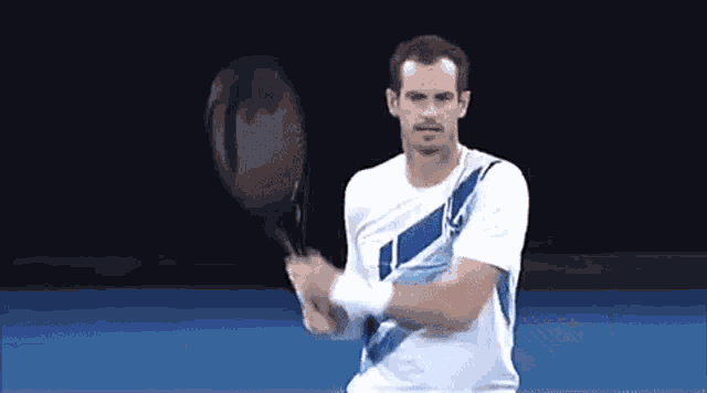 a man in a white shirt is swinging a tennis racquet