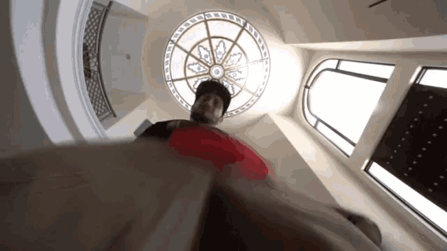 a man in a red shirt is looking up at a stained glass dome ceiling