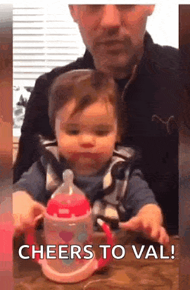 a man and a baby are sitting at a table with a bottle .