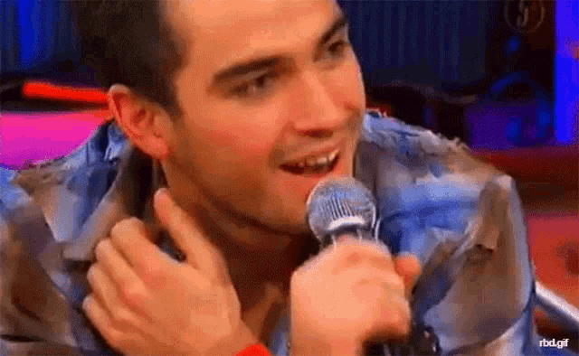a man is holding a microphone in his hand and smiling while talking into it .
