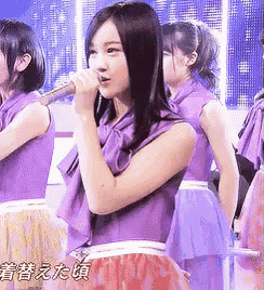 a woman in a purple dress is singing into a microphone ..