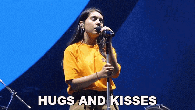 a woman singing into a microphone with the words " hugs and kisses " next to her