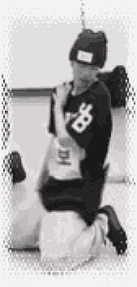 a black and white photo of a person wearing a black hat and kneeling down .