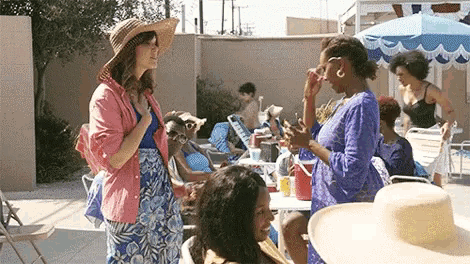 a group of women are standing around a pool with umbrellas .