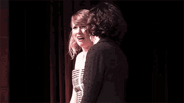 a couple of women standing next to each other on a stage .