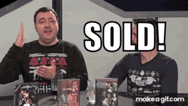 two men are sitting at a table with a sign that says sold on it