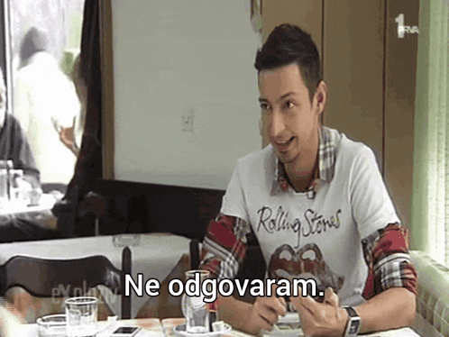 a man wearing a rolling stones t-shirt is sitting at a table