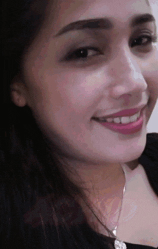 a close up of a woman 's face smiling with a necklace around her neck