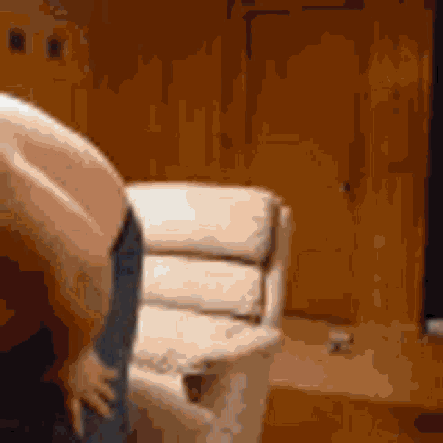 a man without a shirt is bending over in front of a couch .