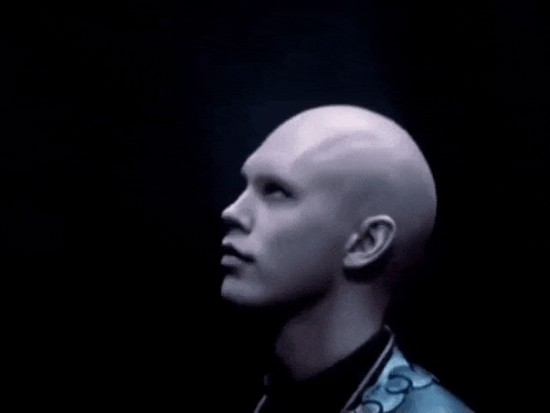 a bald man in a blue suit and tie is looking up at the sky .