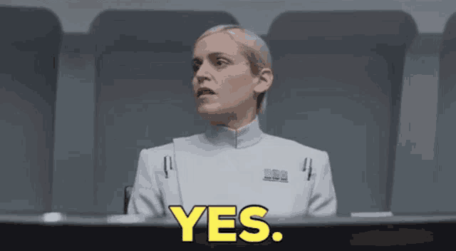 a woman in a white uniform is sitting at a table with the word yes in yellow letters .