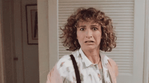 a woman with curly hair is making a funny face while standing in front of a closet .