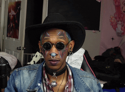 a man wearing a cowboy hat and sunglasses has face paint on