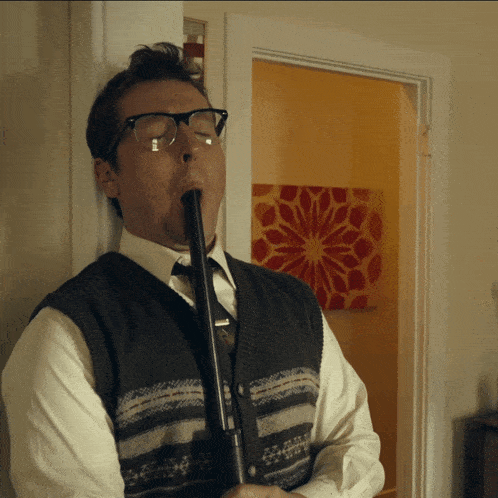 a man wearing glasses and a vest is playing a flute