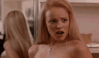a naked woman is looking at herself in the mirror and making a funny face .
