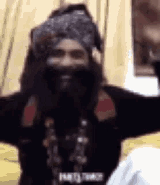 a man with a beard is wearing a turban and a scarf .