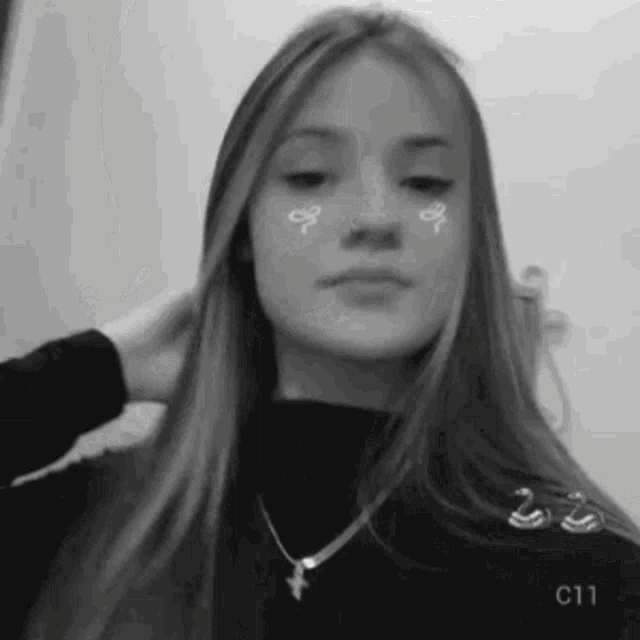 a black and white photo of a young girl with long hair and a necklace .