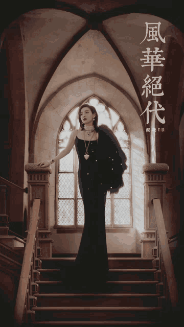 a woman in a black dress stands on a set of stairs in front of a window with chinese writing on it
