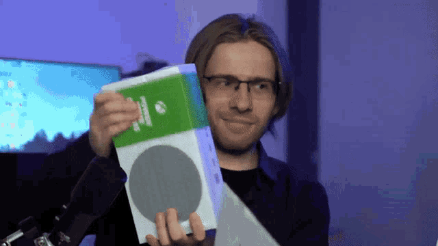 a man with glasses is holding up a box that says xbox