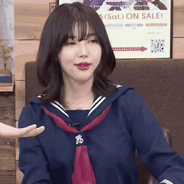 a woman in a sailor suit is sitting in front of a poster that says on sale .