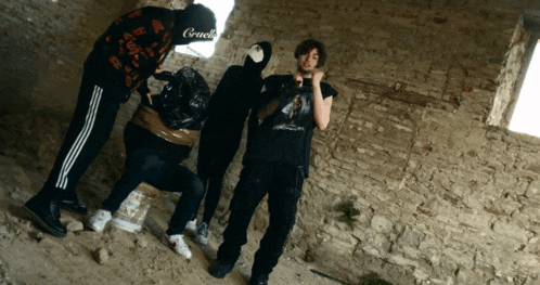 a group of people standing in front of a brick wall with one wearing a sweatshirt that says " cruel "