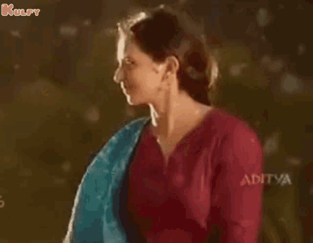 a woman in a red shirt is dancing in the rain with her arms in the air .