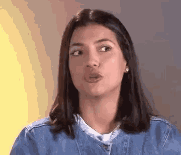 a woman in a denim jacket is making a funny face and making a funny face .