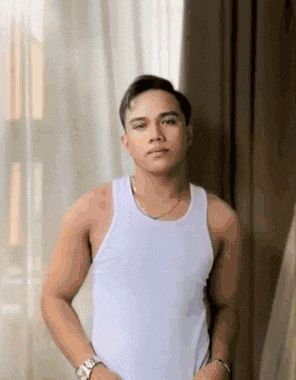 the man is wearing a white tank top and a watch .