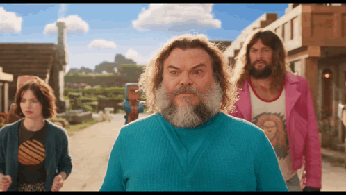 a man with a beard wearing a blue shirt stands in front of a group of people