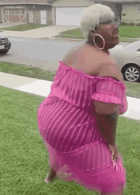 a woman in a pink dress is standing on the sidewalk in front of a house .