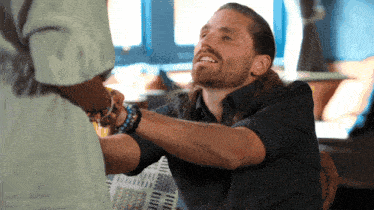 a man with long hair and a beard is talking to a woman