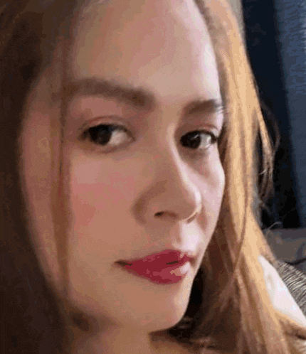 a close up of a woman 's face with long hair and red lipstick .