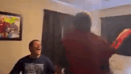 a group of people are dancing in a living room while a man is laughing .