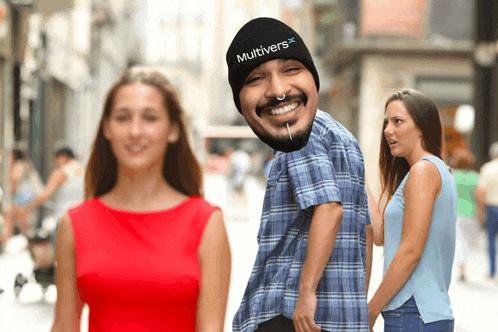 a man with a beanie that says multivers on it smiles while a woman looks on