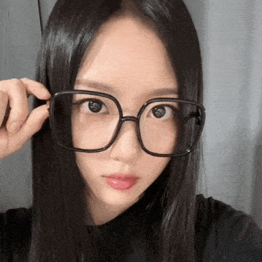 a woman wearing glasses looks at the camera with a serious look on her face